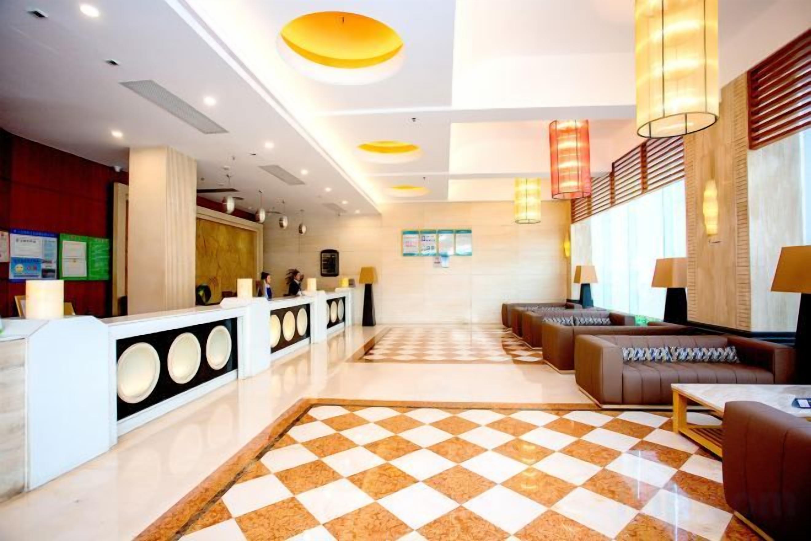 Um saguão de hotel com balcão de recepção, área de estar e balcões de check-in.