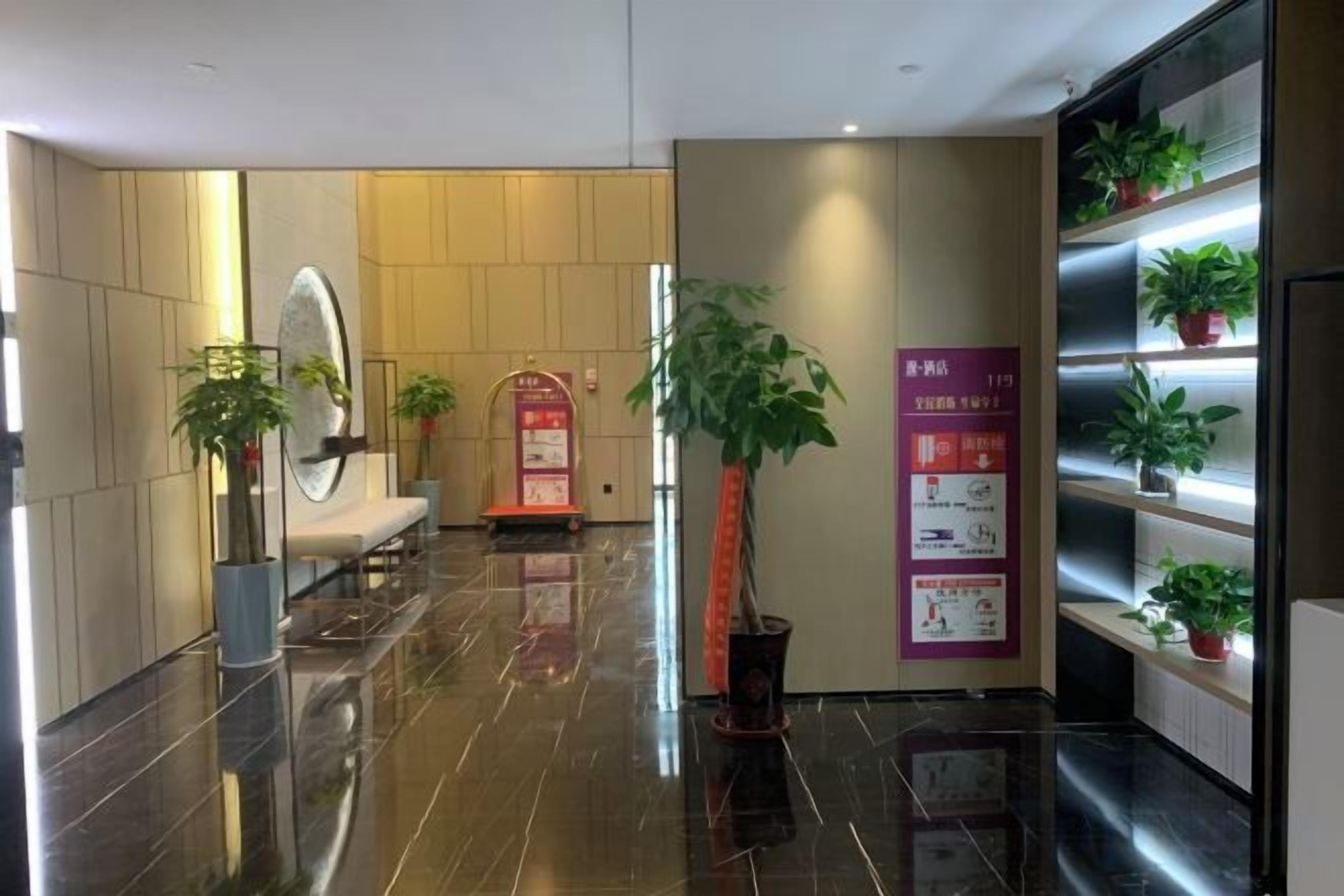 Un vestíbulo de hotel con mostrador de recepción, zona de estar y plantas en macetas.