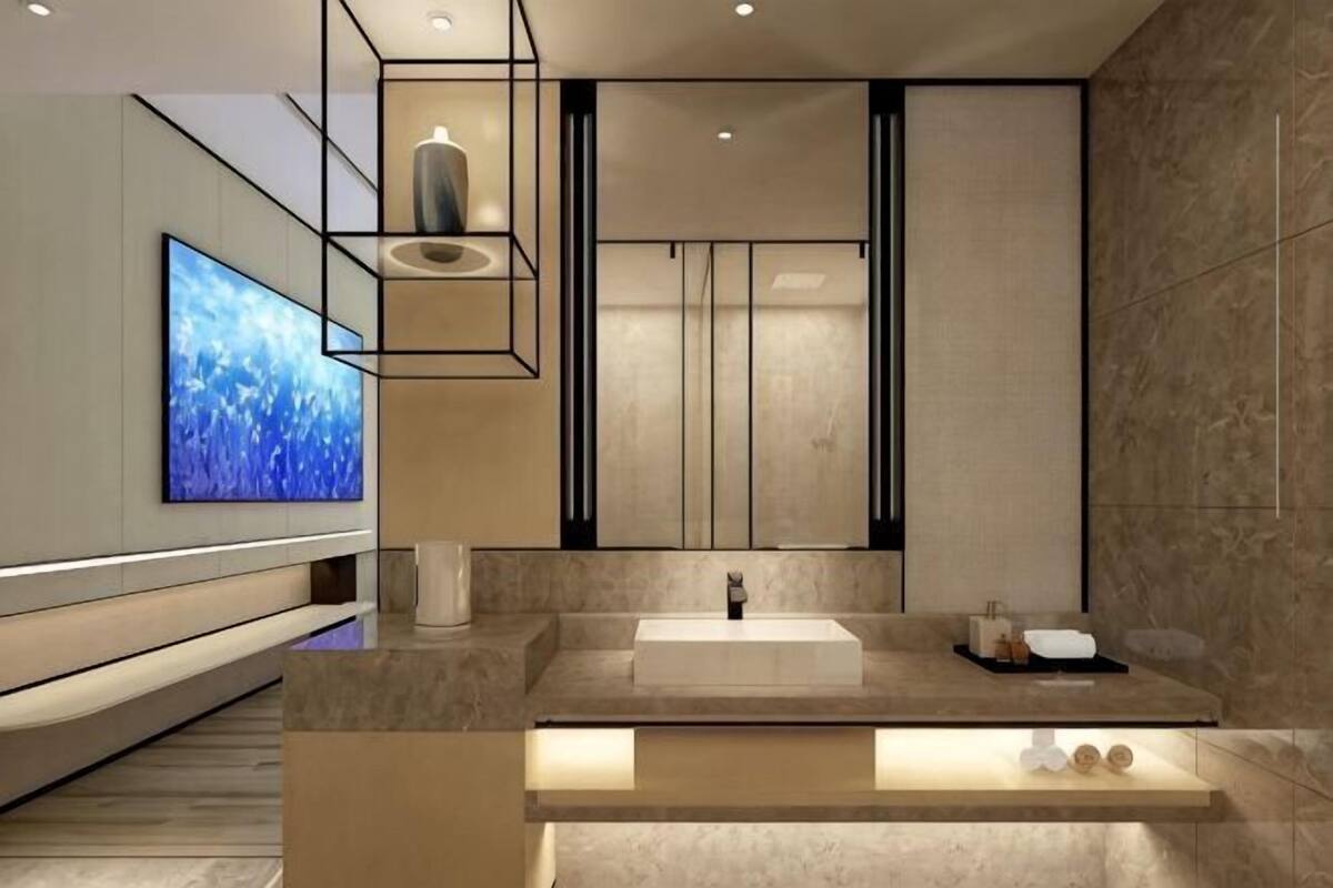 A modern bathroom with a large mirror, a sink, and a television mounted on the wall.