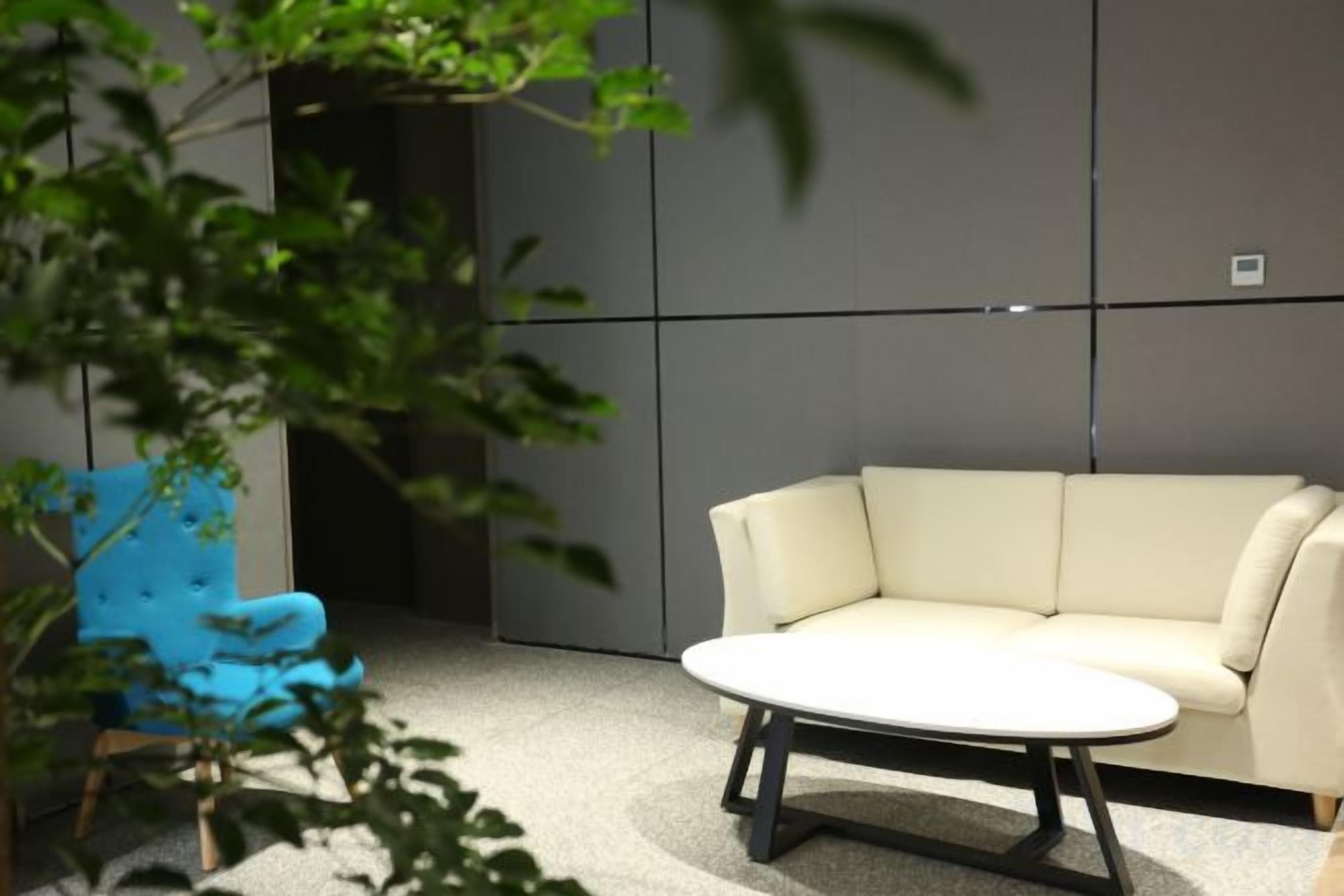 Una habitación moderna con un sofá color beige, una mesa redonda y un sillón azul.