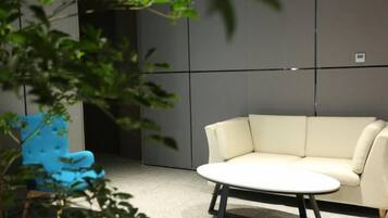 Una habitación moderna con un sofá color beige, una mesa redonda y un sillón azul.