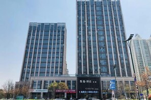 A modern building with multiple floors, likely a hotel or office building, featuring a prominent entrance with signage. - Yi Hotel (Yancheng Champagne Mansion) (Yancheng)