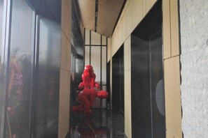 A hallway with a red statue, a glass door, and a wooden wall. - Yi Hotel (Yancheng Champagne Mansion) (Yancheng)
