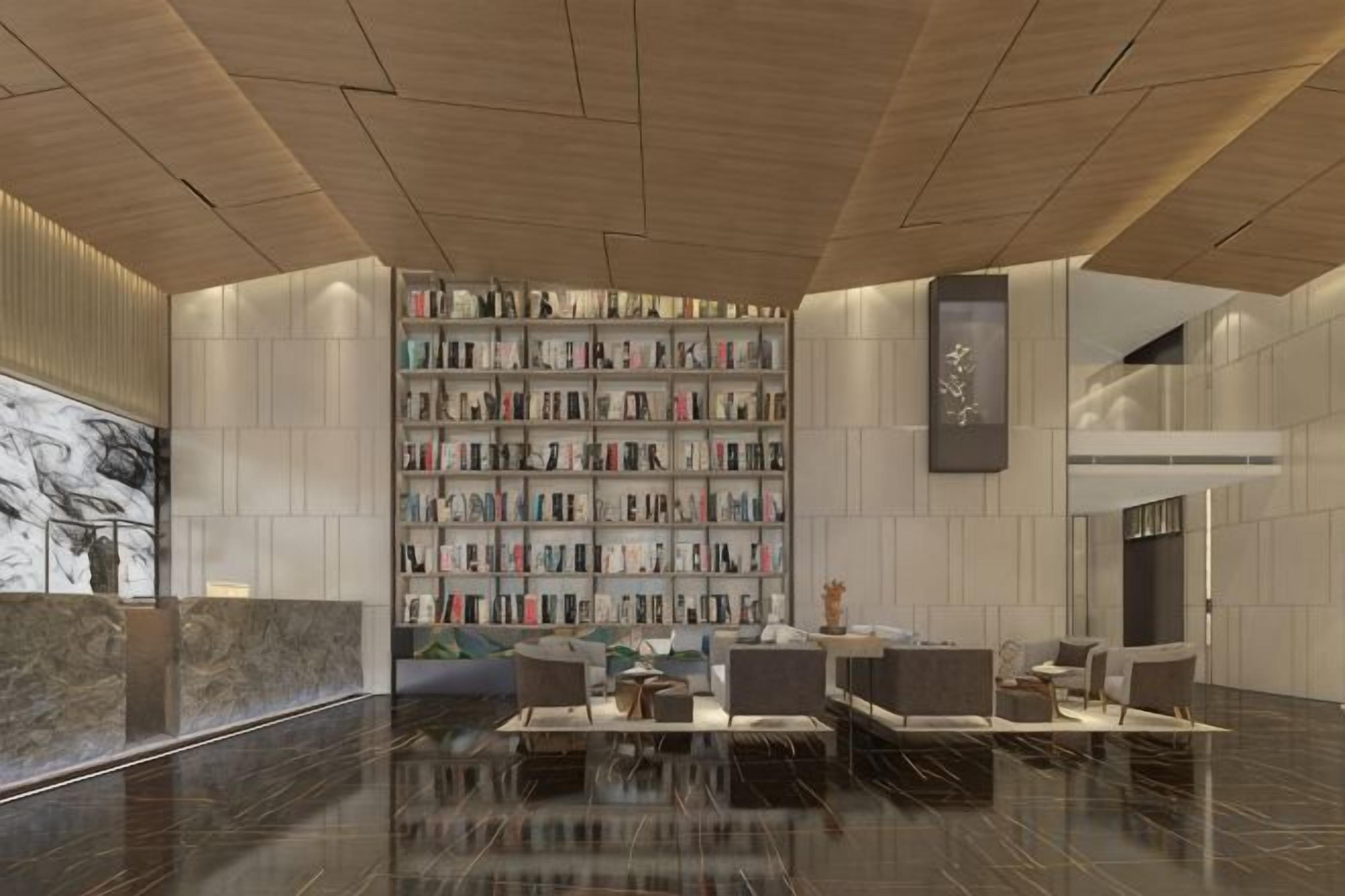 A modern lobby with a marble reception desk, a large bookshelf, and a seating area with sofas and tables.