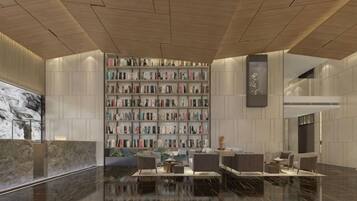 A modern lobby with a marble reception desk, a large bookshelf, and a seating area with sofas and tables.