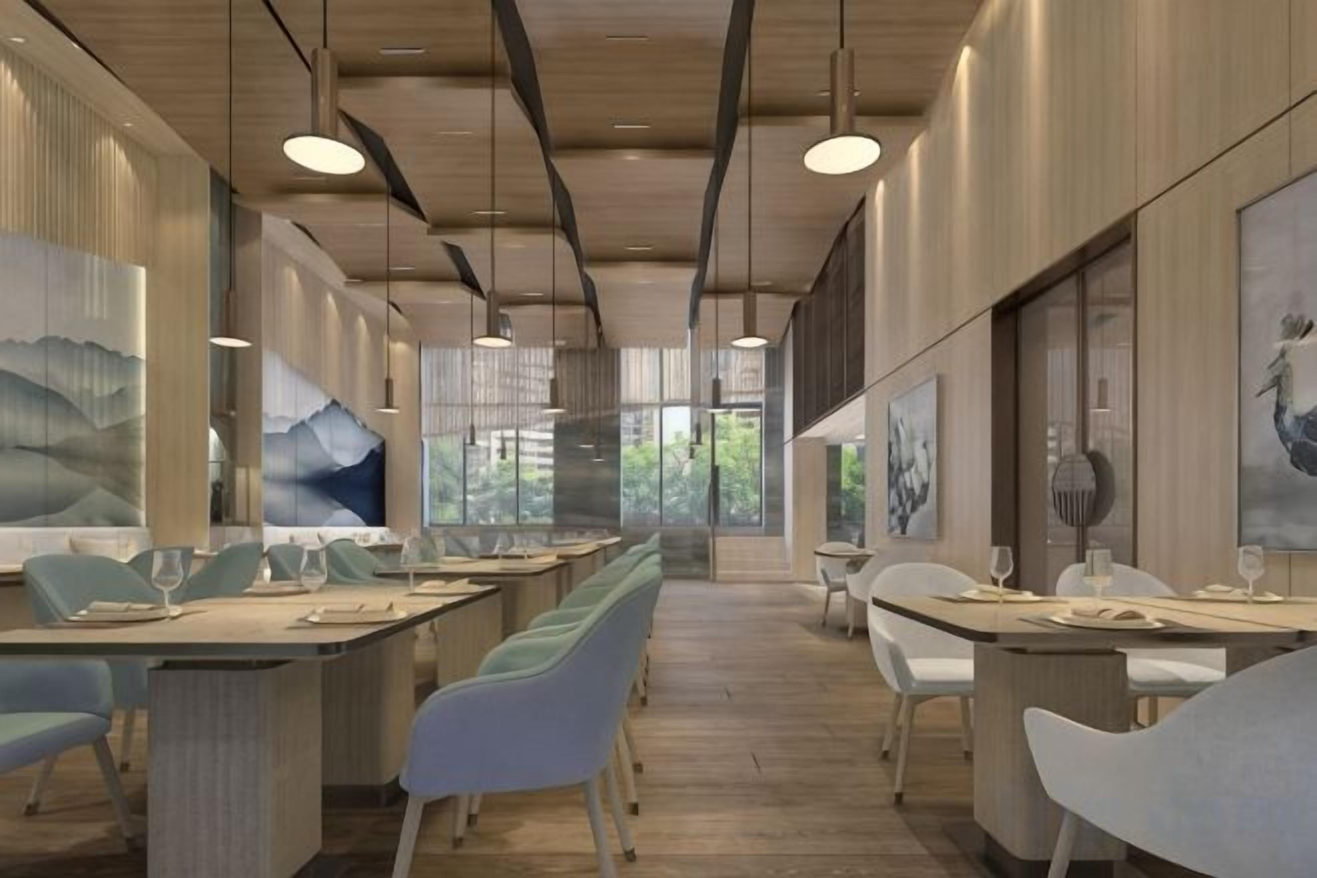 A modern dining area with long tables, chairs, and pendant lighting.