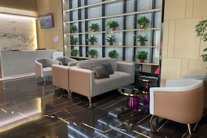 A lobby with a reception desk, seating area, and a wall with potted plants. - Yi Hotel (Yancheng Champagne Mansion) (Yancheng)