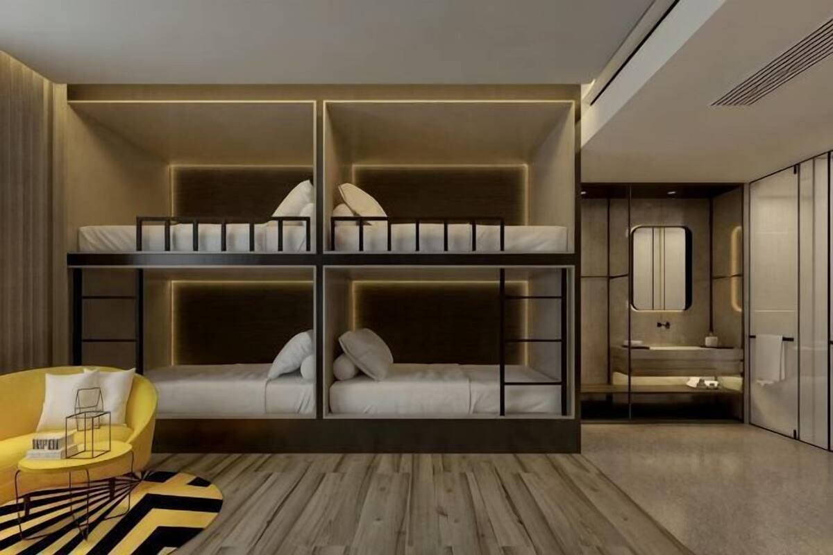 A modern room with bunk beds, a sofa, a small table, and a bathroom with a mirror and sink.