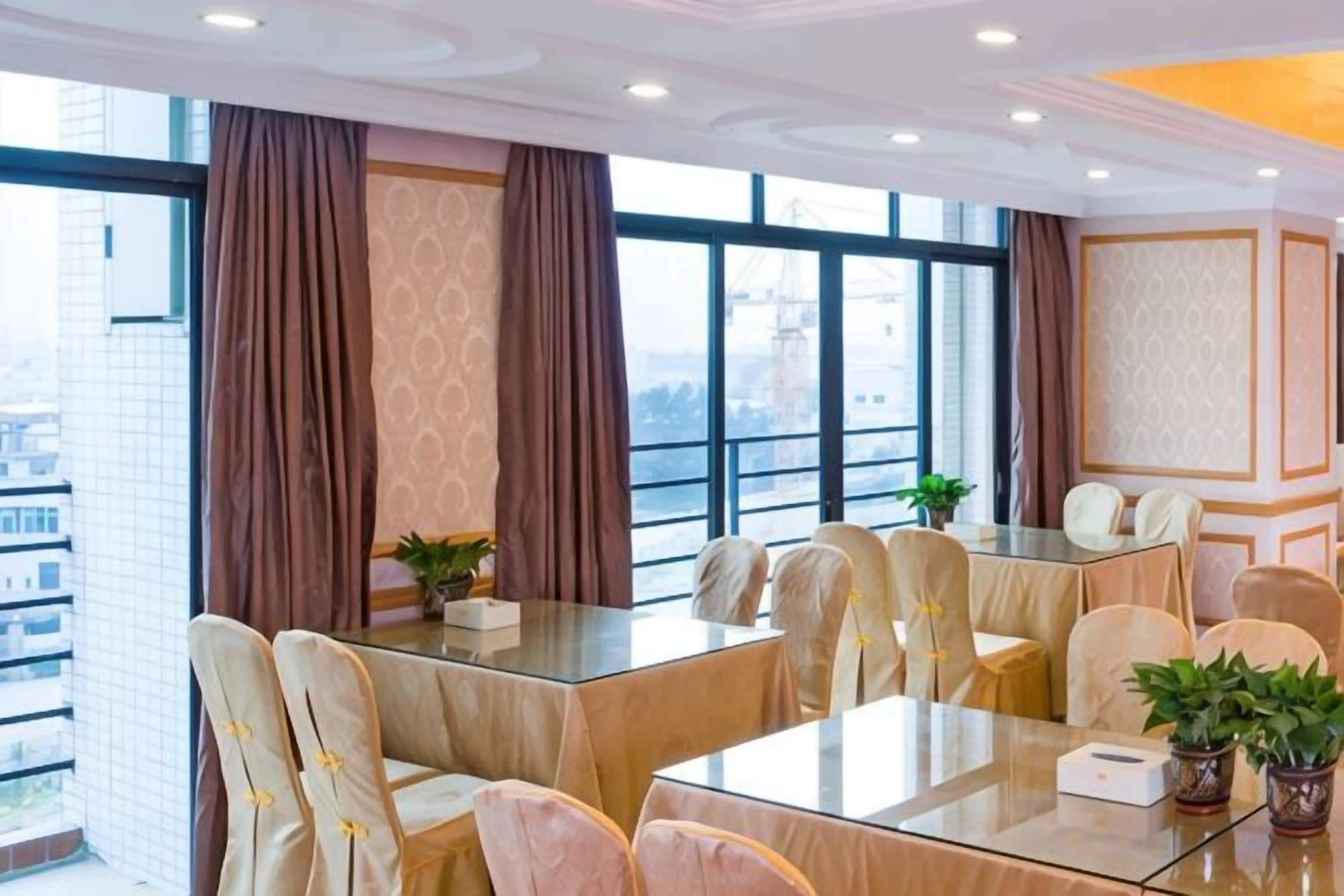 A conference room with a glass table, beige chairs, and large windows with curtains.
