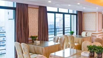 A conference room with a glass table, beige chairs, and large windows with curtains.