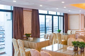 A conference room with a glass table, beige chairs, and large windows with curtains. - Vienna Hotel (Huizhou Yuanzhou) (Boluo)