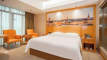 A hotel room with a large bed, two armchairs, a small table, and a nightstand.