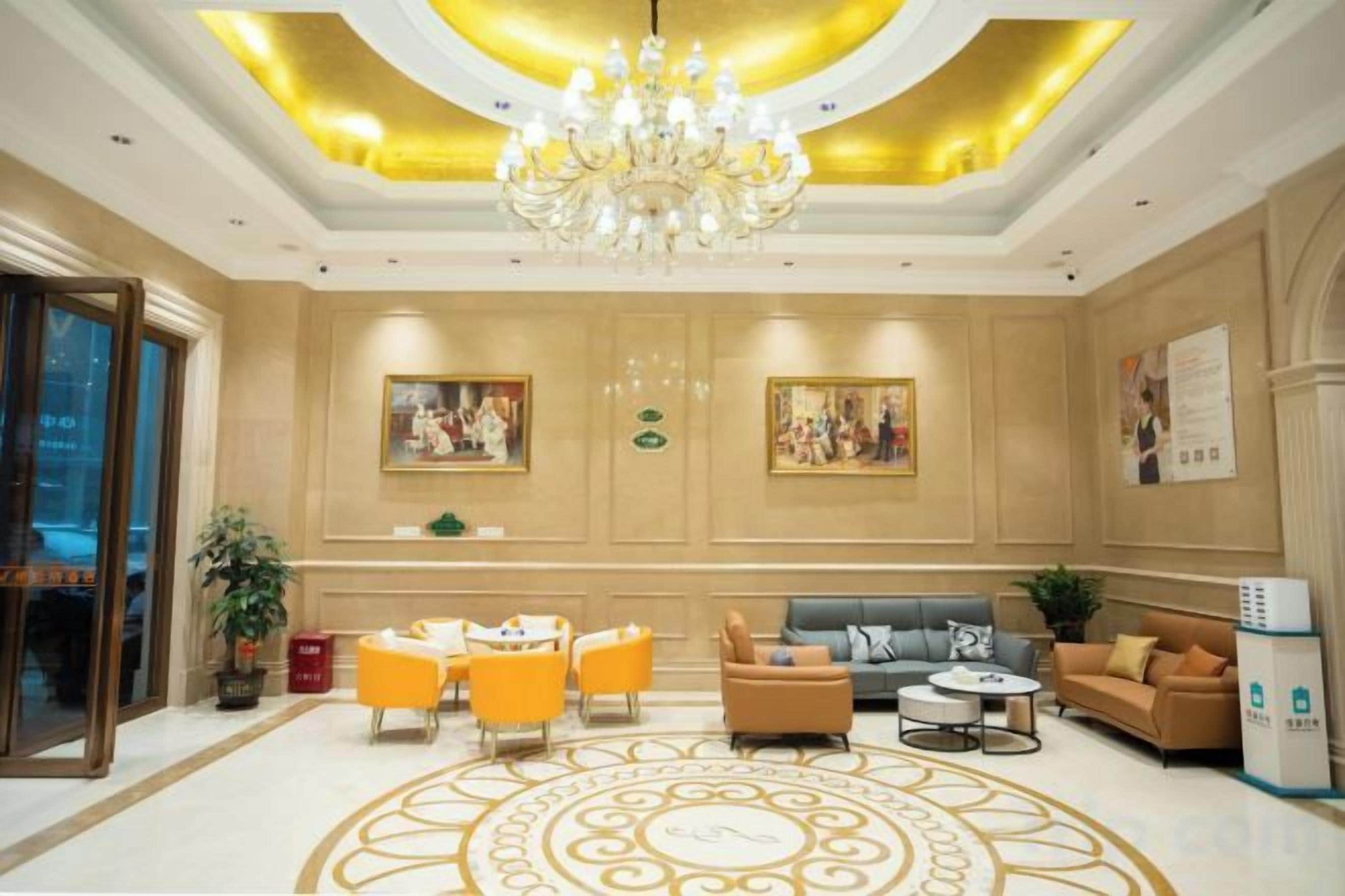 A hotel lobby with a chandelier, seating area, and artwork on the walls.