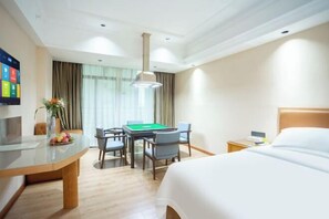 Ein Hotelzimmer mit einem Bett, einem Schreibtisch mit Billardtisch, einem Fernseher und einem Fenster mit Vorhängen.
