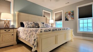 A bedroom with a large bed, bedside tables, and a window with blinds. - Belle Brísa-Canal front Surf City, NC (Surf City)