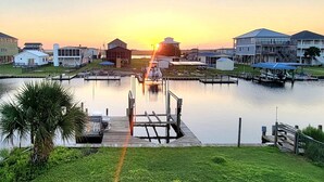 A marina with docks, a small boat, and buildings in the background during sunset. - Belle Brísa-Canal front Surf City, NC (Surf City)