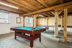 A pool table with a green felt surface, a billiards cue, and a set of balls.