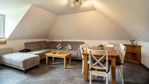 A loft-style living space with a sofa, a dining table, and chairs. - Holiday Apartment 'Nordsee Ferienwohnung Möwe' with Garden and Wi-Fi (Stedesdorf-Thunum)