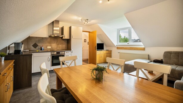 A modern kitchen with a dining area, a sofa, and a window with a view. - Holiday Apartment 'Nordsee Ferienwohnung Möwe' with Garden and Wi-Fi (Stedesdorf-Thunum)