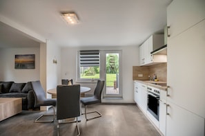 Une cuisine moderne avec un coin repas, de grandes fenêtres et une vue sur l’extérieur.