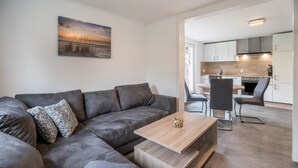 A modern living room with a sectional sofa, a wooden coffee table, and a painting on the wall. - Apartment '9 und 40' with Garden and Wi-Fi (Stedesdorf-Thunum)