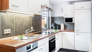 A modern kitchen with a stainless steel sink, a built-in oven, and a microwave.