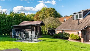A residential property with a patio area, a small wooden structure, and a brick house.