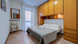 A bedroom with a bed, wooden wardrobe, a radiator, a small wooden chair, and a window with curtains. - Casa Dolce Casa Central Stresa Apt 50m from lake, Stresa, Italy (Stresa)