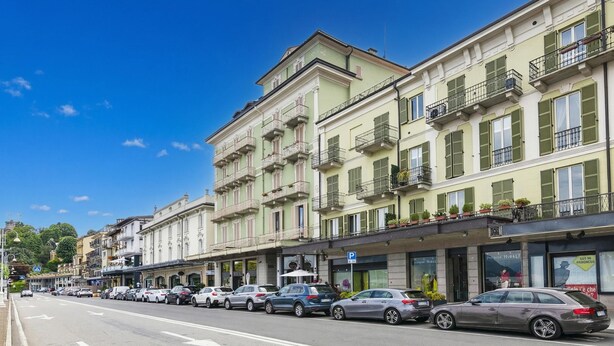 A street lined with multi-story buildings, parked cars, and a clear blue sky. - Casa Dolce Casa Central Stresa Apt 50m from lake, Stresa, Italy (Stresa)