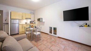 A compact living space with a kitchenette, a dining area, and a flat-screen TV mounted on the wall. - Casa Dolce Casa Central Stresa Apt 50m from lake, Stresa, Italy (Stresa)