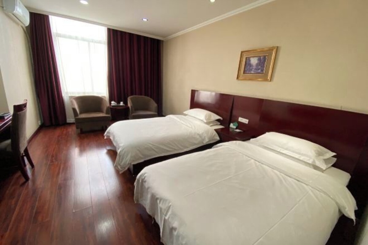 Habitación de hotel con dos camas, una silla, un escritorio y una ventana con cortinas.