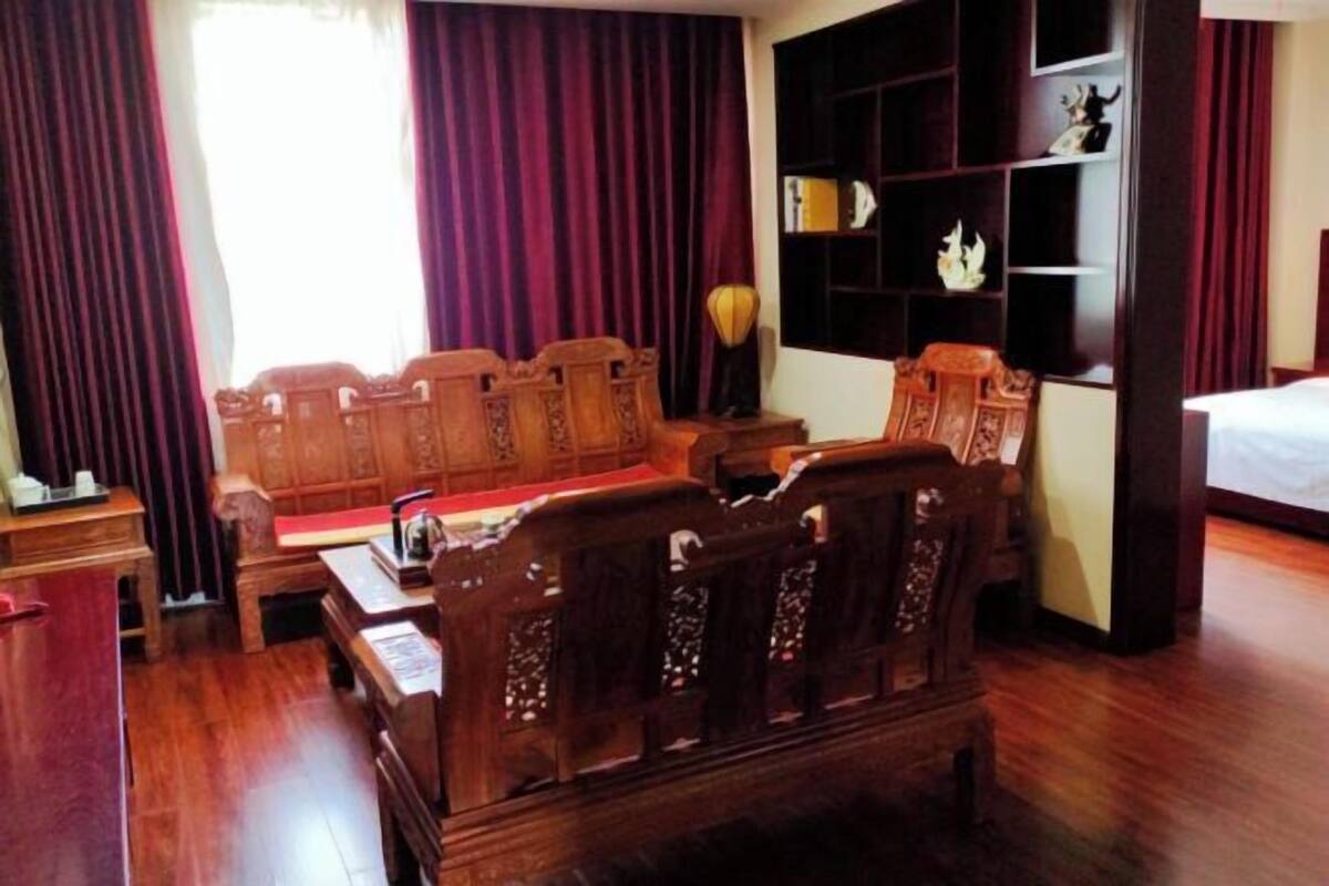 A traditional room with a wooden sofa set, a small table, a bookshelf, and a bed.