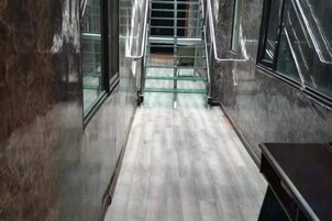 Un pasillo con piso de madera, puertas de cristal y barandilla de metal.
