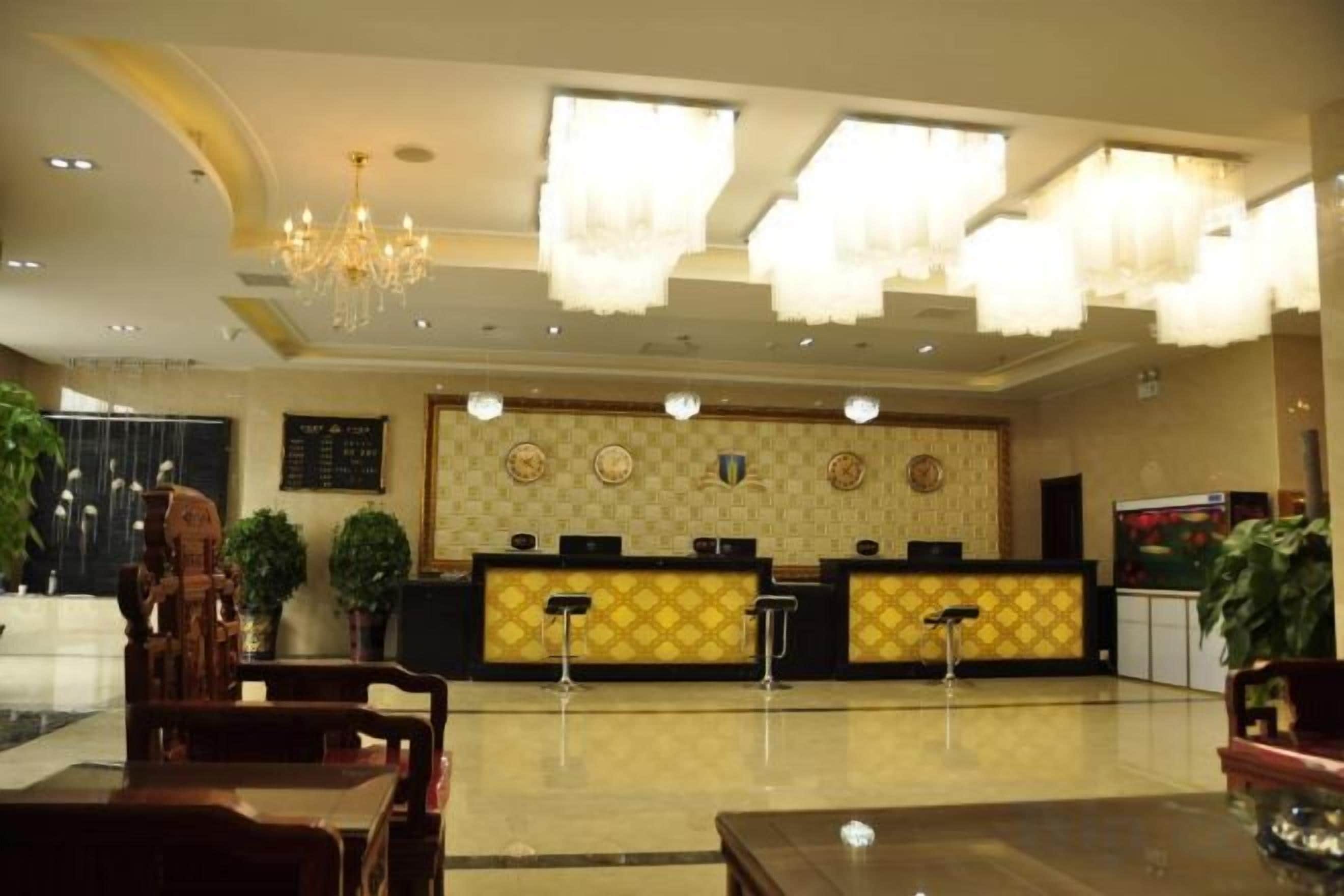 A hotel lobby with a reception desk, seating area, and a chandelier.