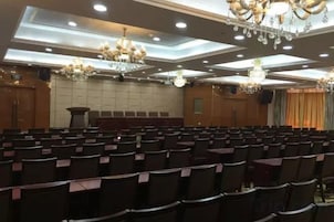 Un salón de conferencias con filas de sillas, un atril y candelabros.
