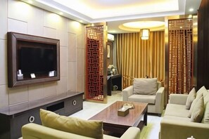 Una sala de estar moderna con un televisor de pantalla plana, dos sofás, una mesa de centro y paneles decorativos de madera.