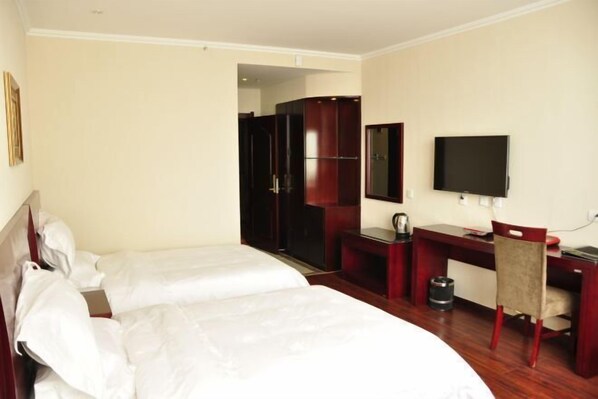 A hotel room with two beds, a desk, a chair, a television, and a wardrobe.