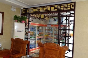 Un hall de hotel con una puerta china tradicional, un refrigerador con una planta en maceta y un refrigerador para bebidas.