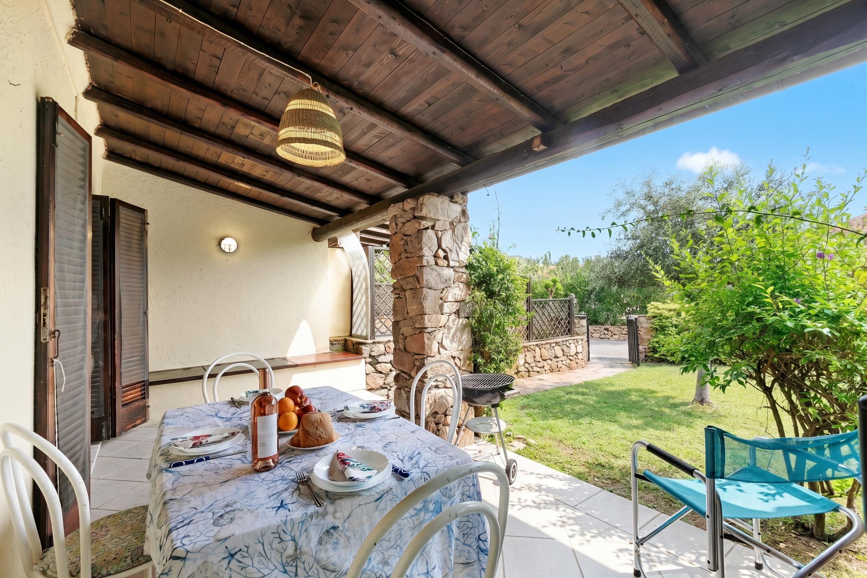 Un patio al aire libre con una mesa lista para comer, un pilar de piedra y vistas al jardín.
