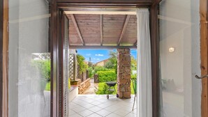An open doorway leading to a patio with a tiled floor, a stone pillar, and a grill.