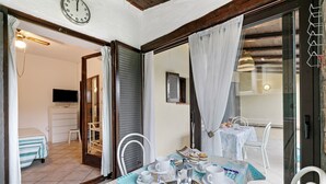 A dining area with a table set for two, a television in the background, and a view of the adjacent room.