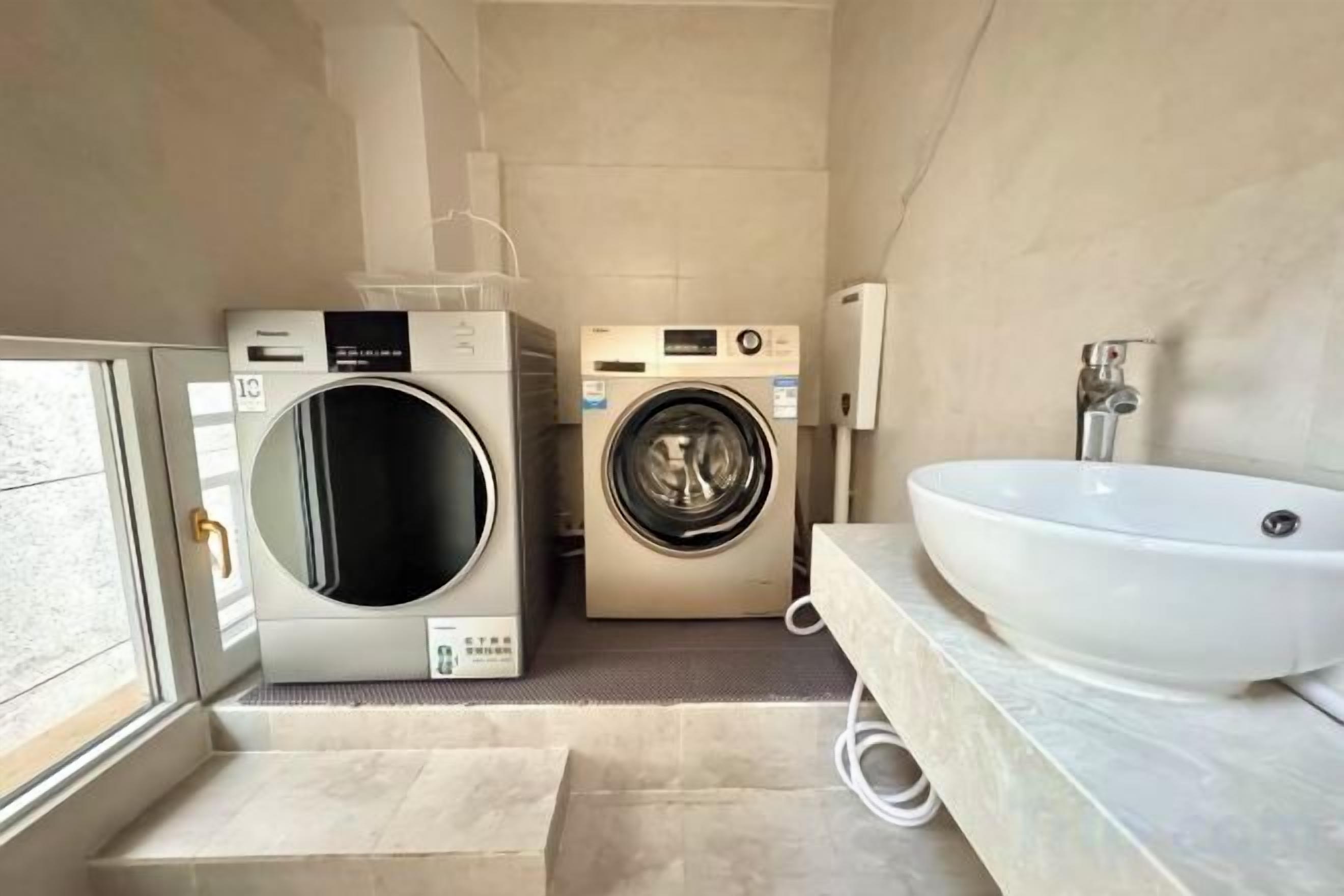 Une petite salle de bain équipée d’un lave-linge, d’un sèche-linge et d’un évier.