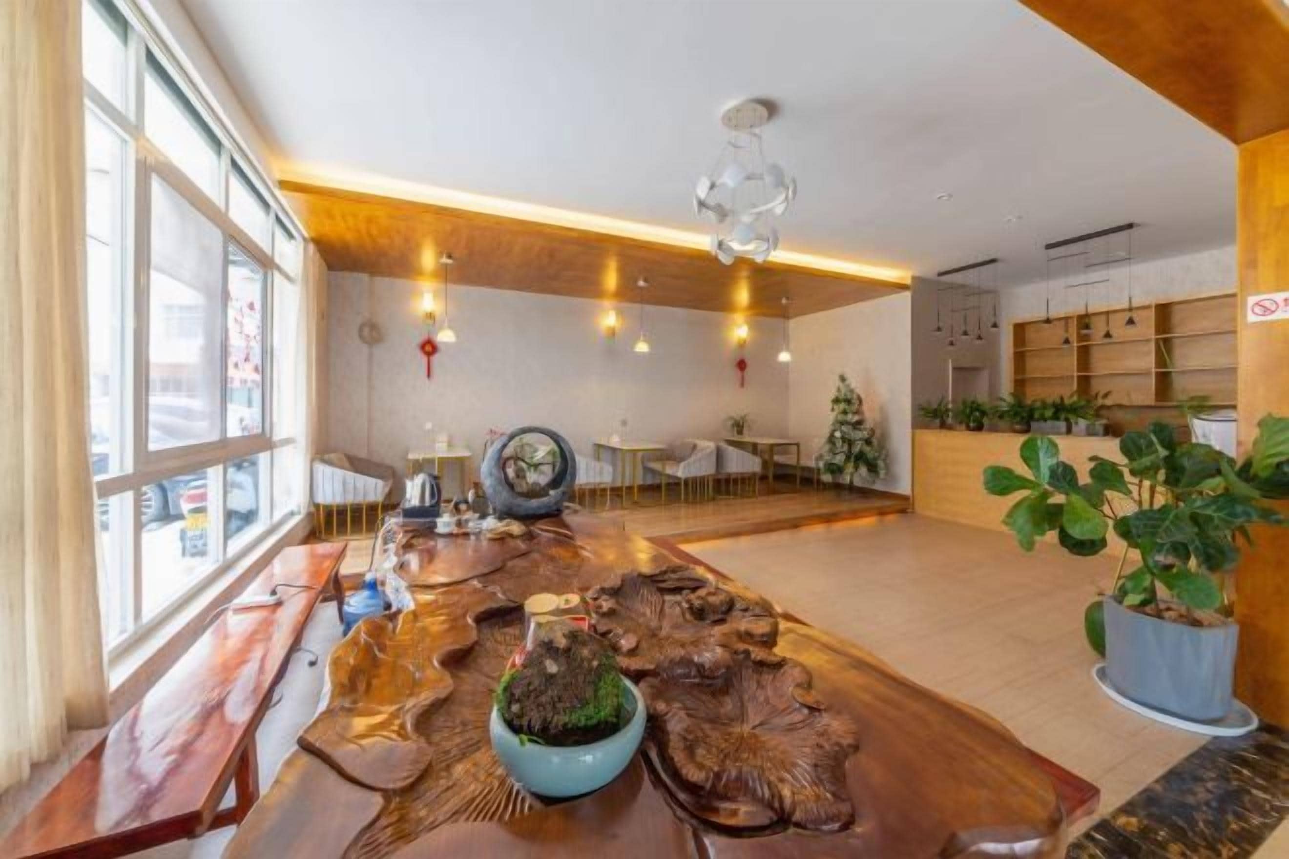 Una habitación amplia con una larga mesa de madera, disposición de asientos y un gran ventanal que proporciona luz natural.