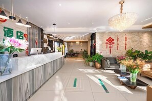 A hotel reception area with a marble counter, a chandelier, and potted plants. - Noah Hotel (Chengjiang)