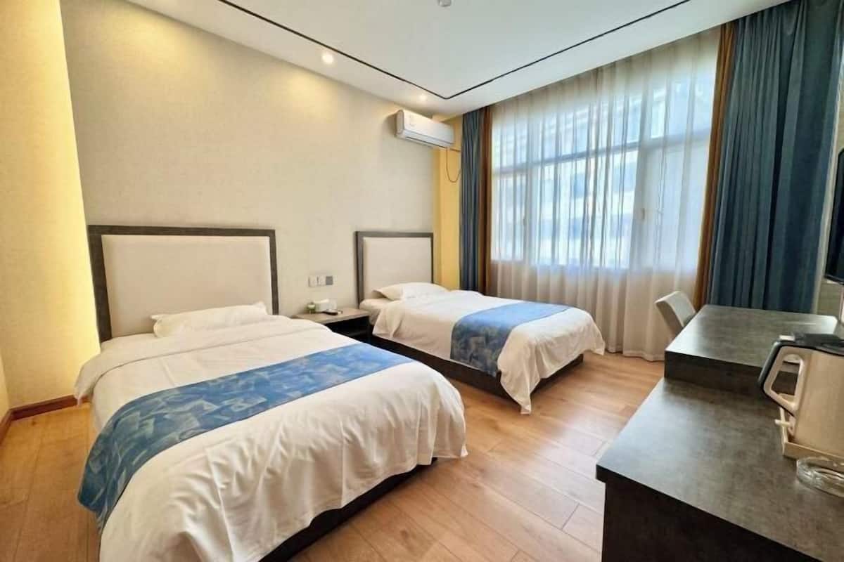 Ein Hotelzimmer mit zwei Betten, einem Schreibtisch und einer Klimaanlage.