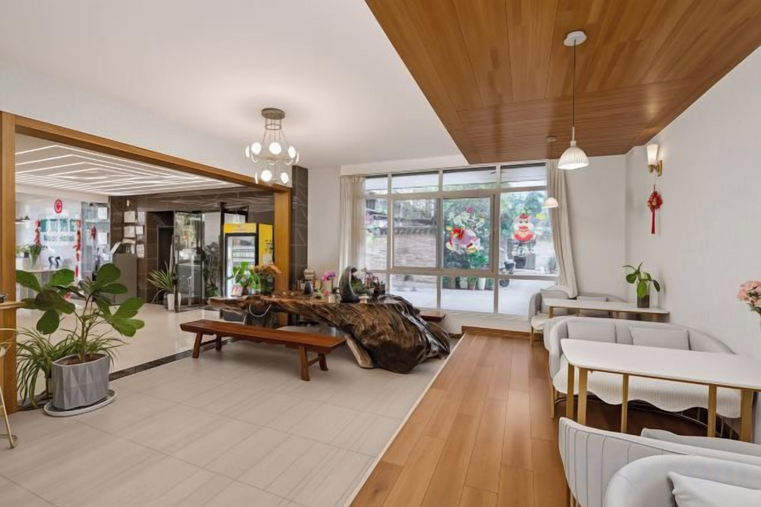 Un'ampia hall con soffitto in legno, una reception e un'area salotto con divani bianchi.