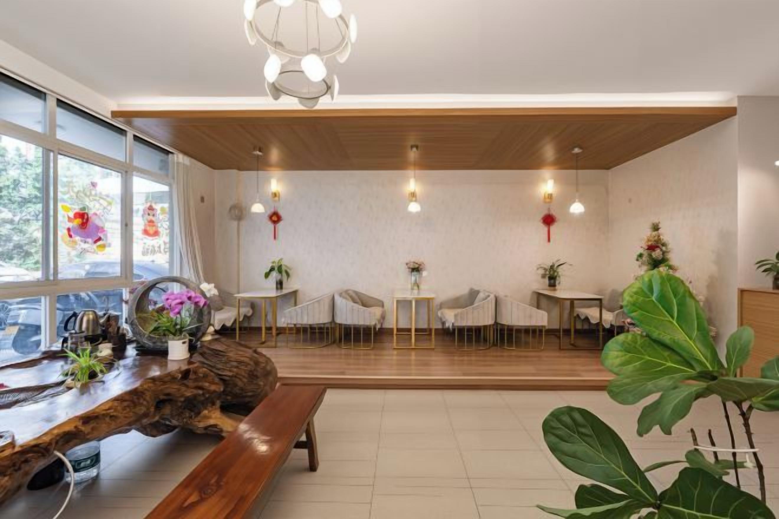 Un interior moderno con techo de madera, una zona de comedor con sillas y mesas, y una planta grande.