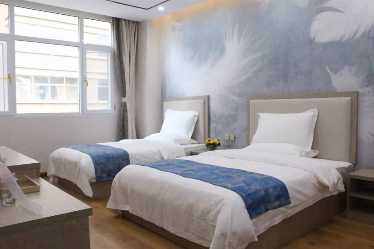 Ein Hotelzimmer mit zwei Betten, einem Schreibtisch und einem Fenster mit Vorhängen.