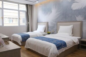 Habitación de hotel con dos camas, un escritorio y una ventana con cortinas.