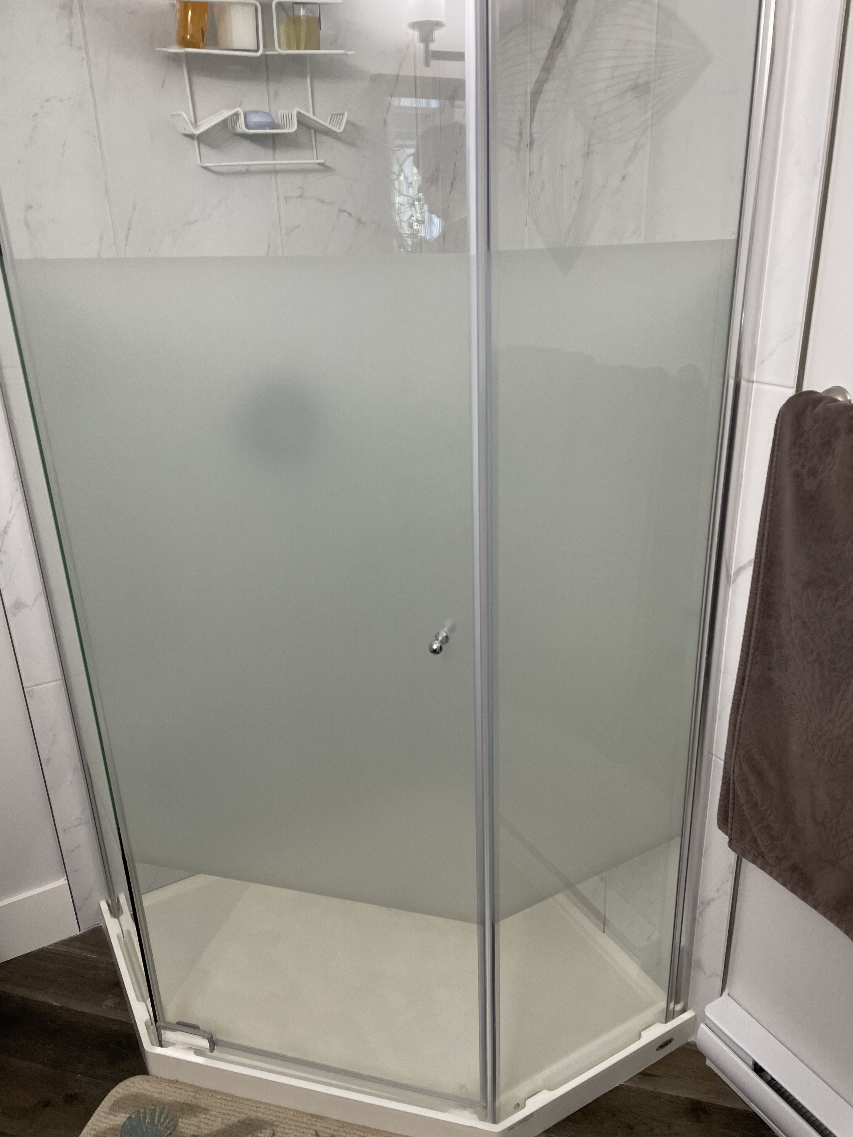 A glass-enclosed shower area with a white base and a glass door.